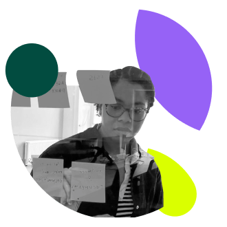 A grayscale photograph of a young Black woman with glasses, looking down and working with sticky notes on a surface, is overlaid with large, abstract shapes: a dark green circle, a purple leaf shape, and a lime green leaf shape. The woman is wearing a striped shirt under a dark jacket. The sticky notes have handwritten text on them.