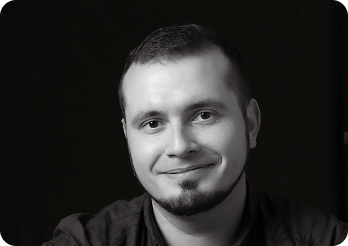 Black and white image of a man (Alexey, Senior Full Stack Engineer at Systemseed) smiling.