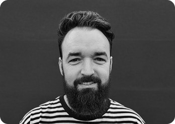 Black and white image of a man (Dave, UX/UI designer at Systemseed) smiling.