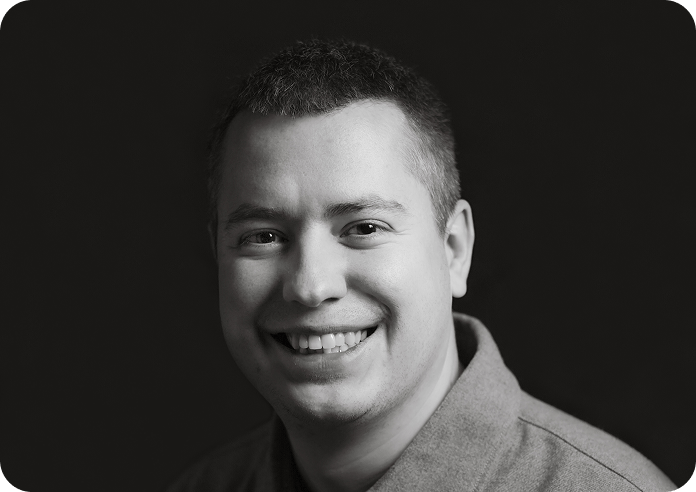 Black and white image of a man (Evgeny, CTO at Systemseed) smiling.
