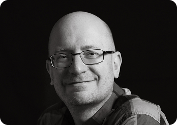 Black and white image of a man (Leo, Technical Lead at Systemseed) smiling.