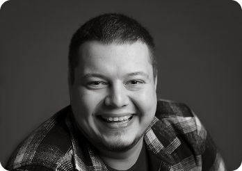 Black and white image of a man (Pavel, Senior Full Stack Engineer at Systemseed) smiling.