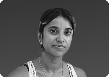 Black and white studio portrait of a woman looking directly at the camera against a solid dark background.