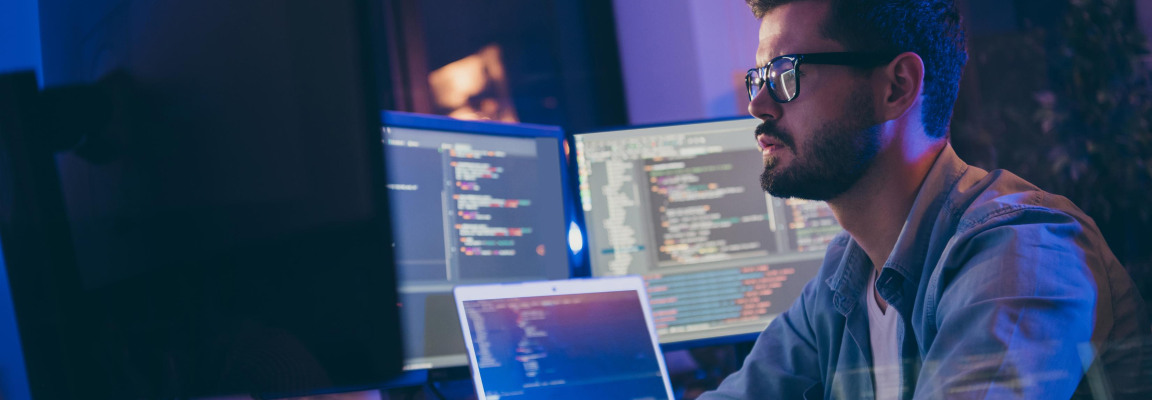 Man at desk with several computer monitors