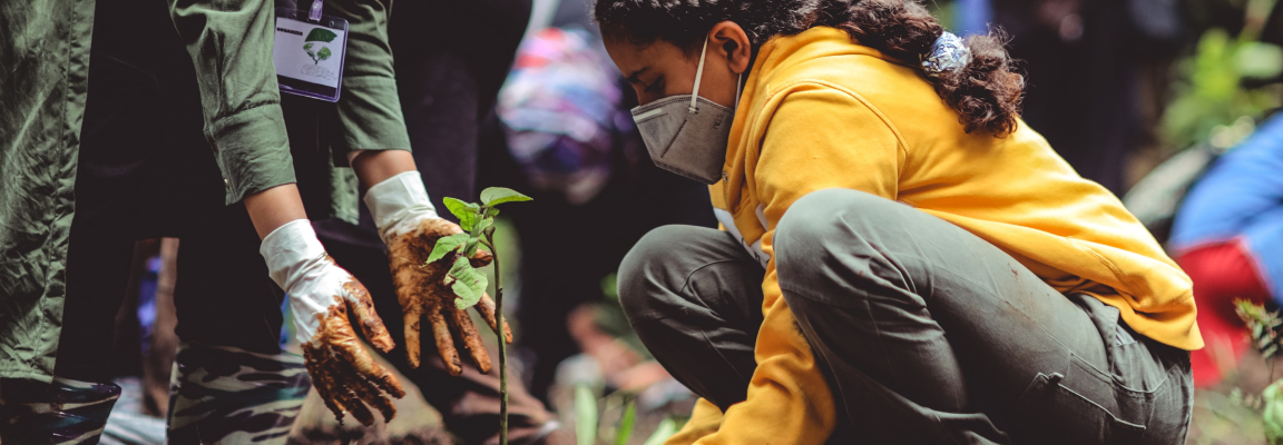 Girl wearing mask planting a tree