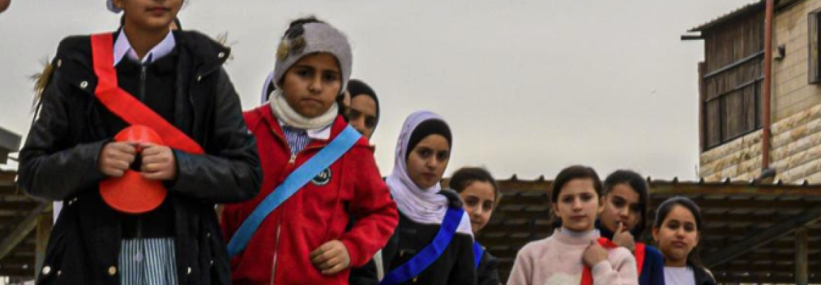 Image of children in a line in the playground, wearing coloured sashes War Child Holland photograph from WeACT