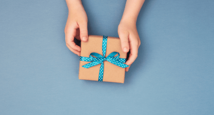 small gift wrapped in brown paper and blue ribbon on blue background