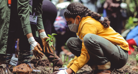 Girl wearing mask planting a tree