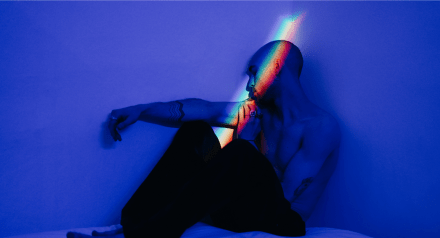 Man sitting on bed in blue light